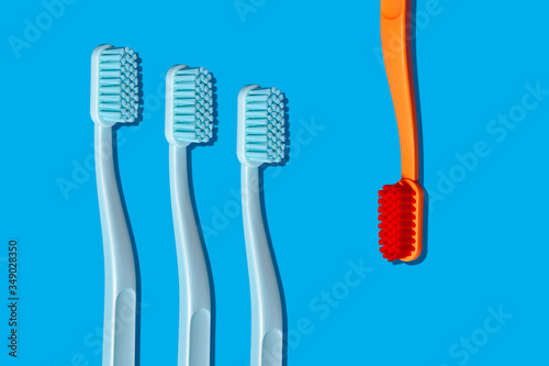 Modern Monochromatic Orange and Blue Toothbrushes Laying on Blue Background in Pattern (ID: 349028350)