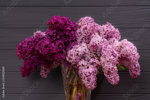 Blooming lilac flowers in the vase on grey wall background
