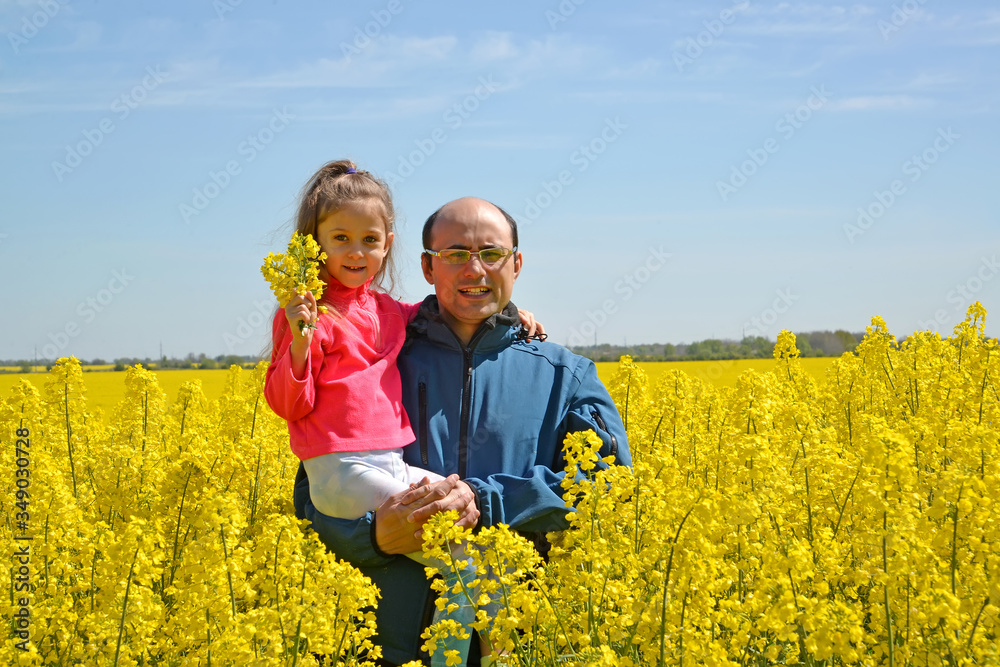 Man with daughter on hand standing in flowering rapeseed field Man with daughter on hand standing in flowering rapeseed field