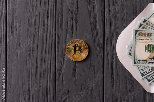 Opened envelope with dollar bills and bitcoin golden coin isolated on grey wooden background
