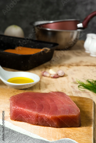 Piece of tuna meat on wooden board with kitchen in the background