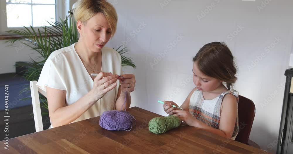 Mother and daughter crocheting at home