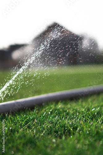 Irrigation system in the field. A broken hose leaks water. Green beautiful background. Village garden