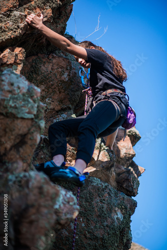 A strong woman struggles up a steep rock face