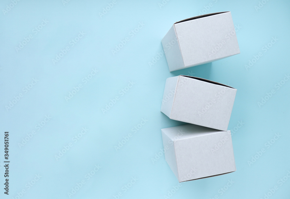 White cardboard boxes for product packaging and delivery to customers. Square boxes fall from above on a blue background. Selective focus. Space for text. Copy space White cardboard boxes for product packaging and delivery to customers. Square boxes fall from above on a blue background. Selective focus. Space for text. Copy space