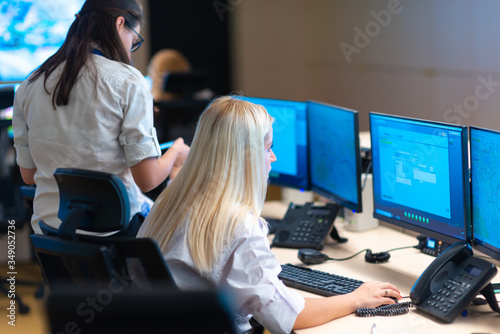 Security guards standing in front of a large CCTV monitor at the main control room while reading and discussing plans