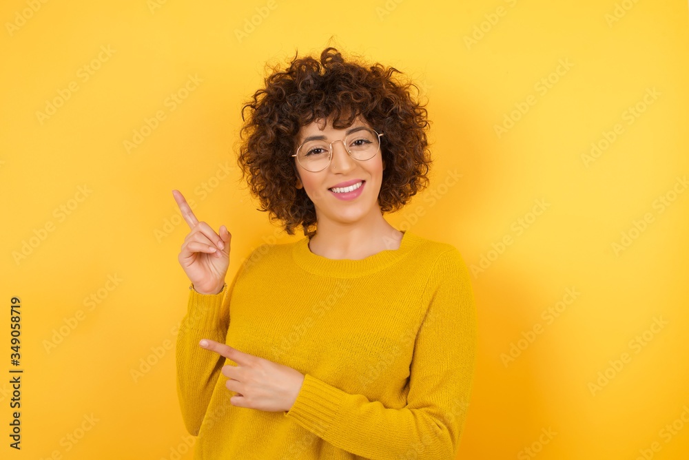 Photo of pretty young lady indicating with forefinger empty space showing best low prices wear stylish yellow sweater isolated yellow color background Photo of pretty young lady indicating with forefinger empty space showing best low prices wear stylish yellow sweater isolated yellow color background