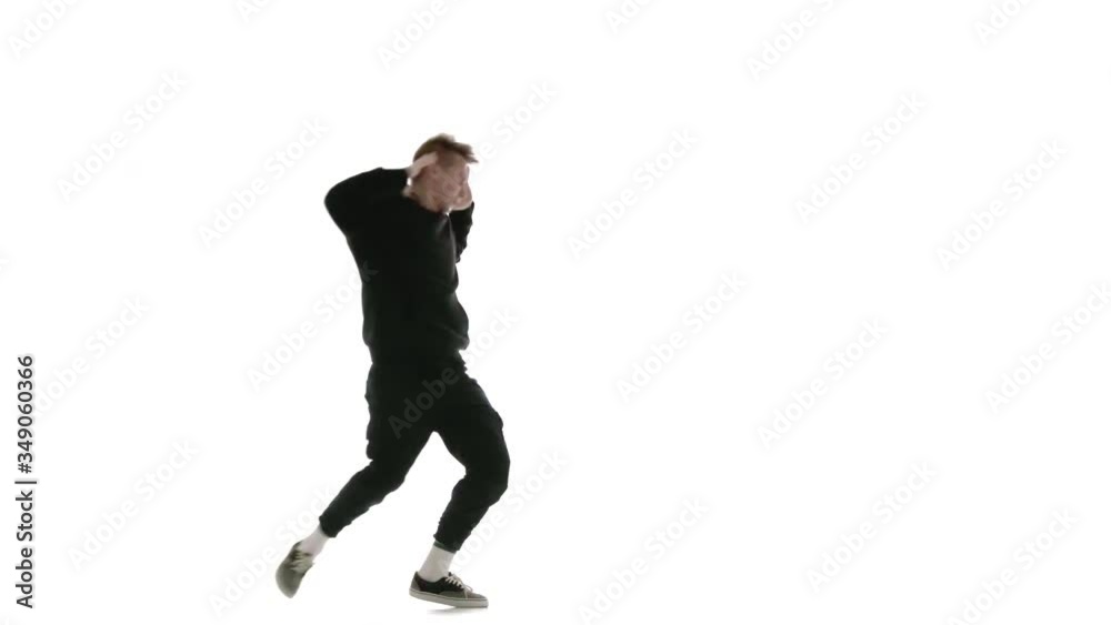 young handsome man in black tracksuit vigorously dancing hip hop, freestyle, street dance, performs complex movements, isolated, slow motion