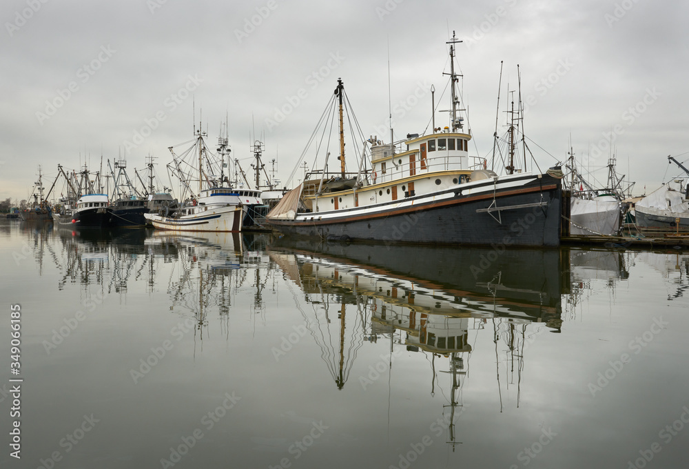 Steveston Fishboats at Dock. Calm water and clouds over the harbor of Steveston, British Columbia, Canada near Vancouver. Steveston is a small fishing village on the banks of the Fraser River.

