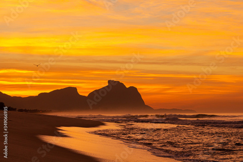 Amanhecer na praia com a mar batendo na areia 