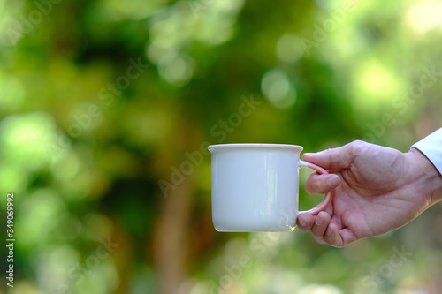 hand holding cup of coffee on green background