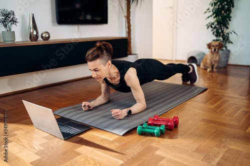 woman doing exercise while watching tutorial on laptop at home