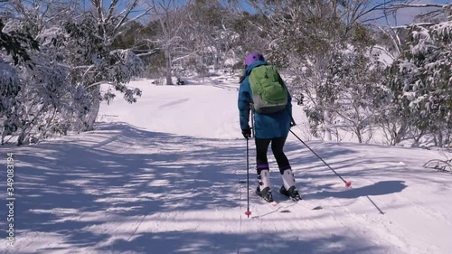 Women intermediate skiing down groomed ski slope photo