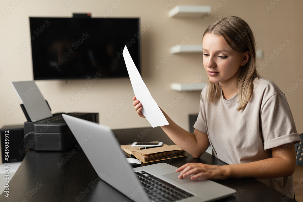 A beautiful, lovely girl does the work from home, smiles and checks the information from the document on the computer during quarantine. A beautiful, lovely girl does the work from home, smiles and checks the information from the document on the computer during quarantine.