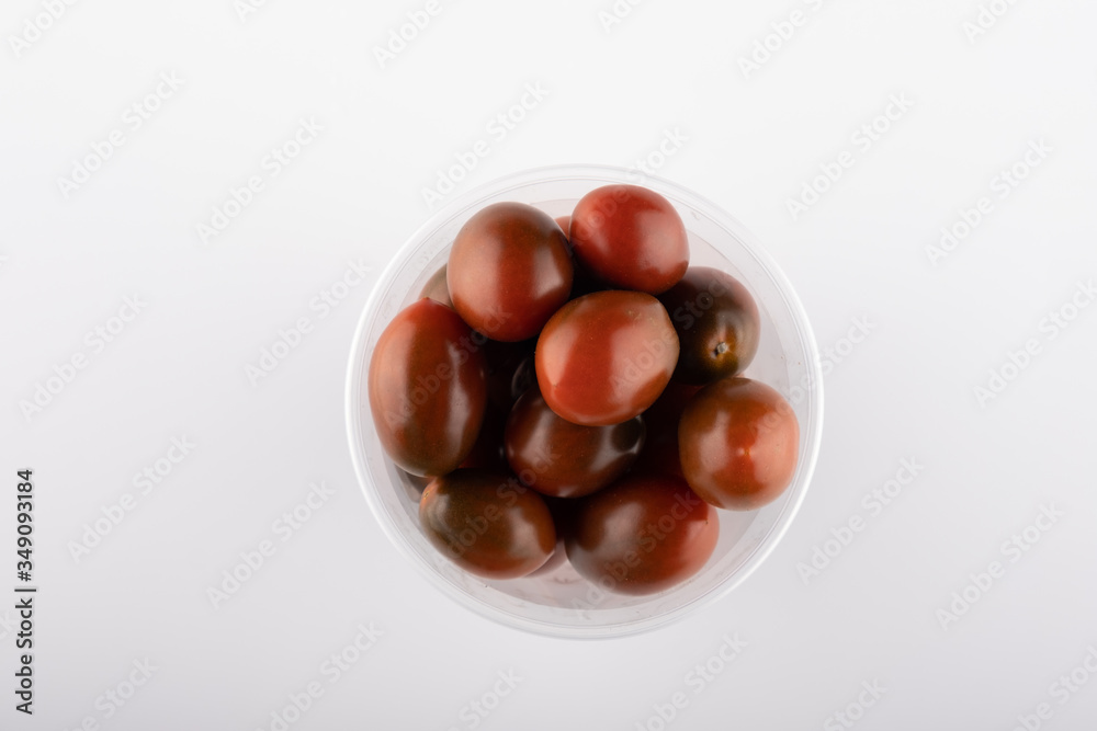 multi-colored tomatoes in a plastic box close-up on a white background multi-colored tomatoes in a plastic box close-up on a white background