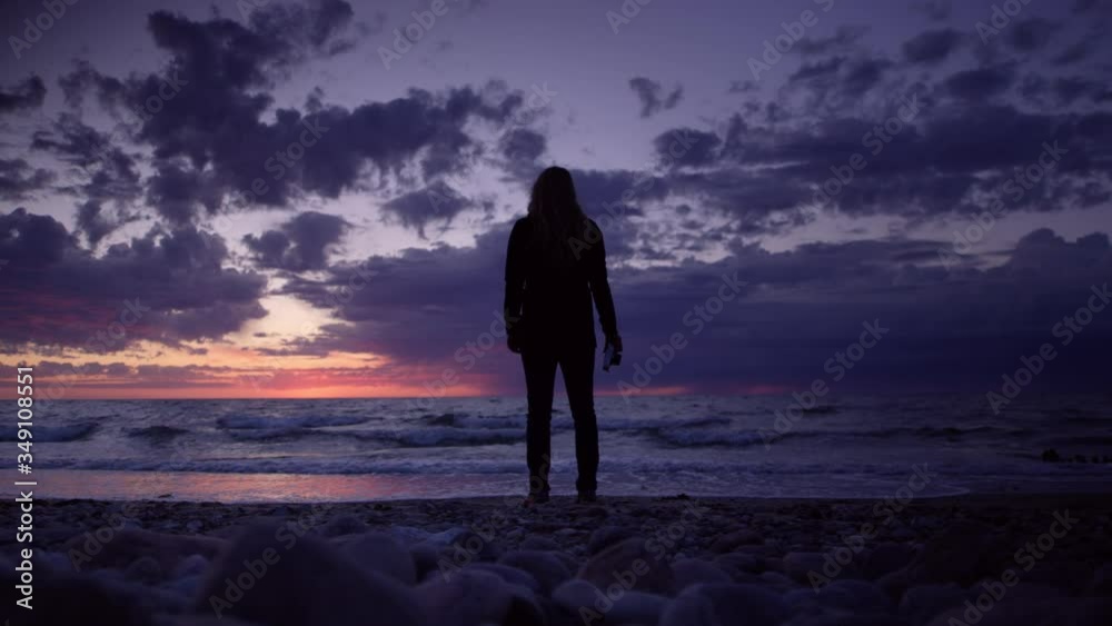 Silhouette of Adventurous Woman Holding a Camera with Dramatic Ocean Sunset Background Silhouette of Adventurous Woman Holding a Camera with Dramatic Ocean Sunset Background