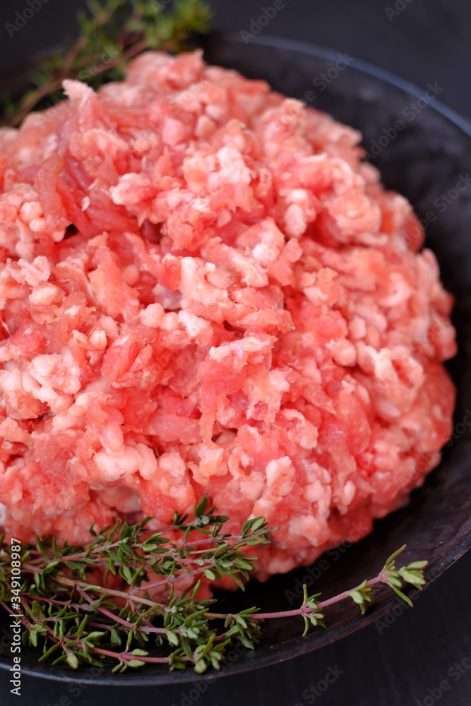 forcemeat with sprigs of thyme in a black cup on a black background.Meat food. Ground chopped meat and spicy herbs.Minced pork.Protein food.Texture of fresh cut forcemeat forcemeat with sprigs of thyme in a black cup on a black background.Meat food. Ground chopped meat and spicy herbs.Minced pork.Protein food.Texture of fresh cut forcemeat