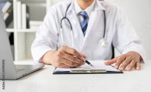 Doctor holding the patient report file to assess symptoms on the desk.