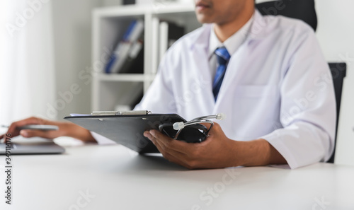 Doctor holding the patient report file to assess symptoms on the desk.