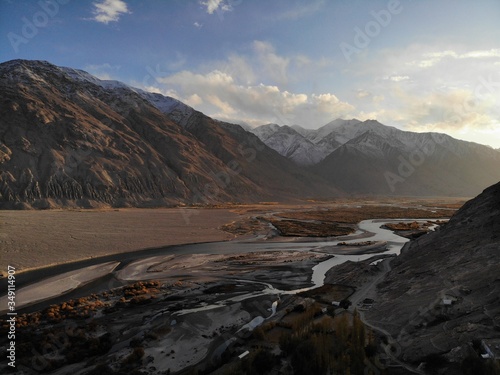 Mountain road. White peaks. Dangerous cliffs. Pamir. Fast river. Rocks. Dangerous road. Roof of the world. Talikistan. Badakhshan.Traveling in the mountains. Afganistan.