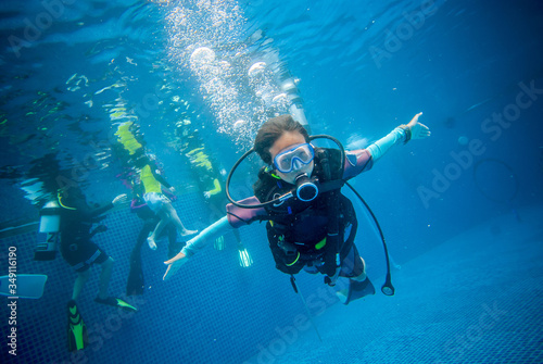 Underwater, a 10 year old boy diving in a pool with fun. This is diving for children.