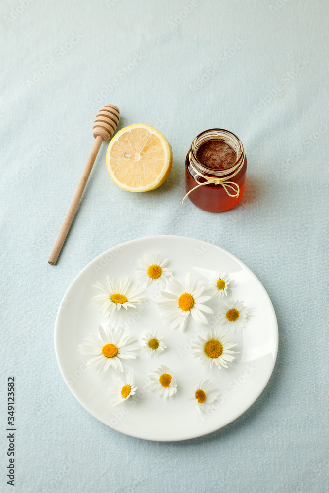 Chamomile flowers and chamomile tea. Chamomile tea in glass teacup with flowers, honey and lemon, top view, prevention of seasona flu colds Chamomile flowers and chamomile tea. Chamomile tea in glass teacup with flowers, honey and lemon, top view, prevention of seasona flu colds