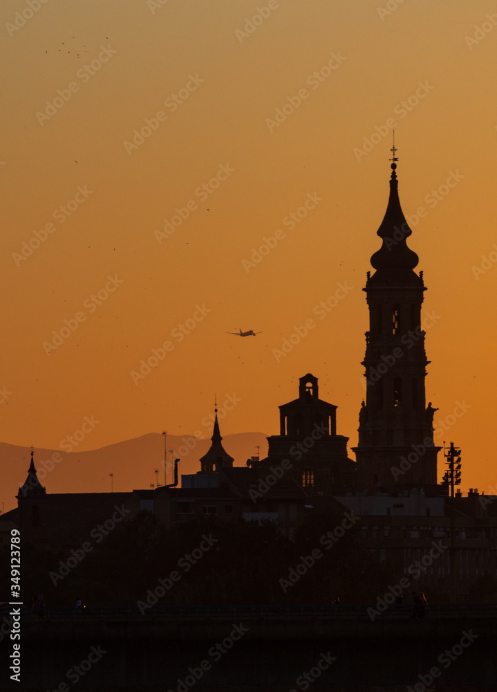 Naklejka premium sunset in Zaragoza with the cathedral in the background and a plane taking off