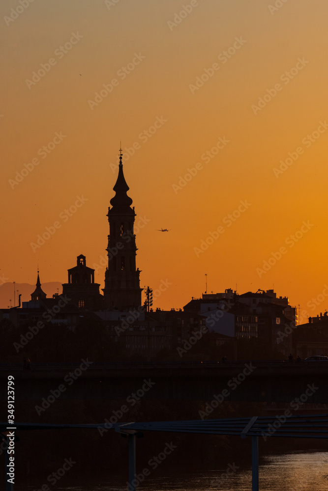 sunset in Zaragoza with the cathedral in the background  and a plane taking off