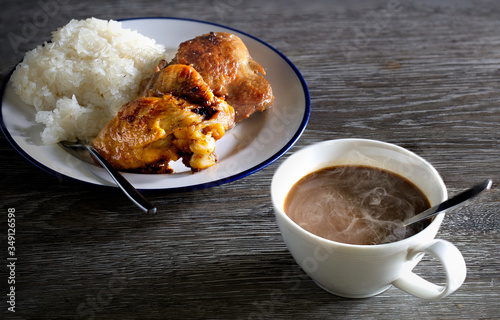 Fried chicken with sticky rice on white dish and hot coffee all put on gray wooden table photo