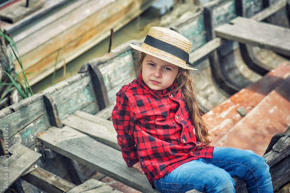 Portrait of a charming little girl in a straw hat in nature