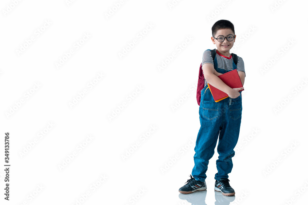 Naklejka premium Asian school boy holding book and smiling at camera on white background, with clipping path