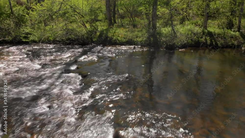 Narrow rippling water cascades over rocks in clear river, forward aerial Narrow rippling water cascades over rocks in clear river, forward aerial