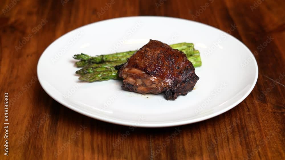 Chicken thigh and asparagus being presented on plate 4k