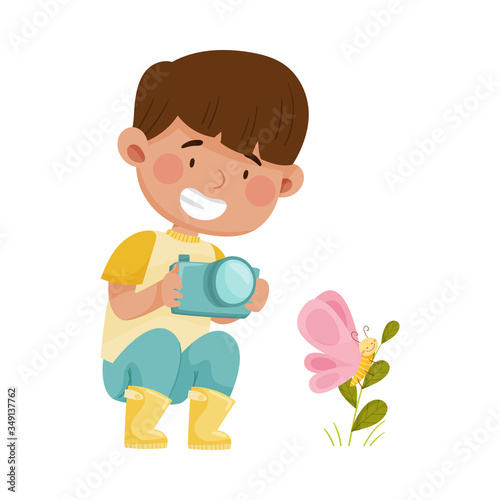 Little Boy Hunkering Down with Camera Taking Photo of Butterfly Sitting on Grass Vector Illustration