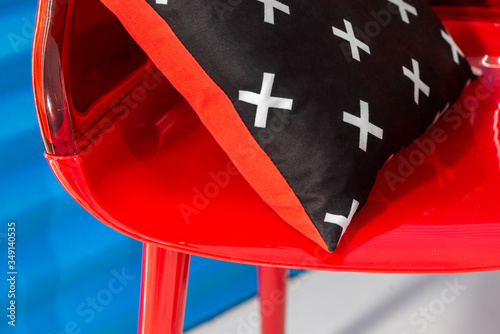 Red chair with black-white cross-printed and red pillow on it. Close-up interior photo. photo