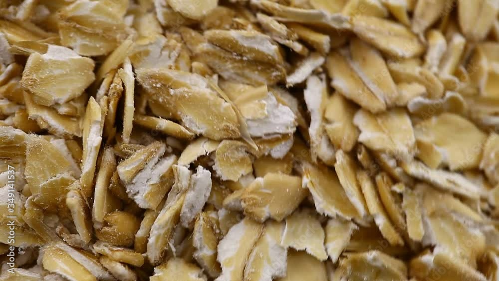 Oat flakes in bulk rotate, top view, spinning slowly in a circle, close up.