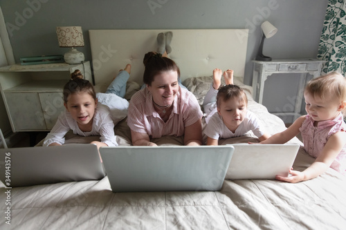 Mom and Three siblings kids on bed with laptops