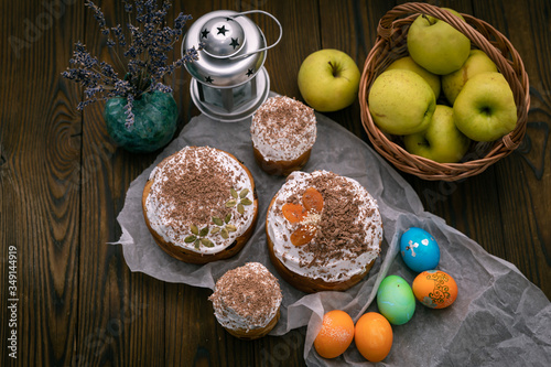 Easter cakes, eggs and apples in the basket. On the brown table.