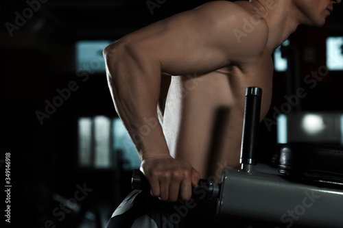 Strong man working out on parallel bars in modern gym, closeup