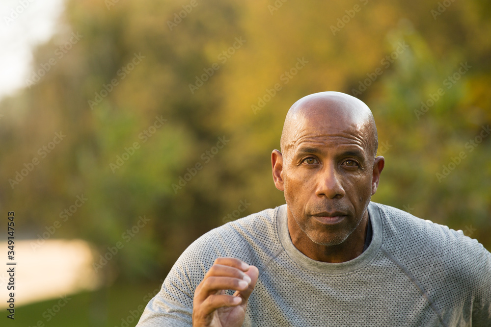 Mature fit African American man running outside.