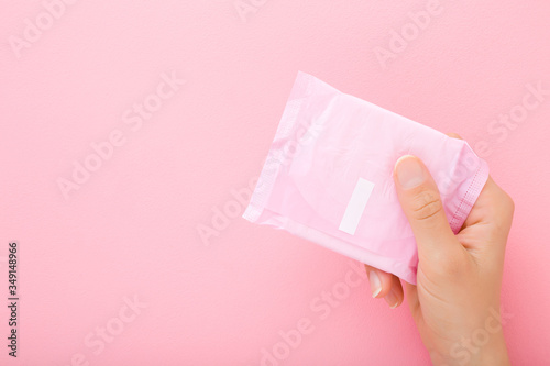Konstfotografi Young woman hand holding pack of sanitary towel on light pink table background