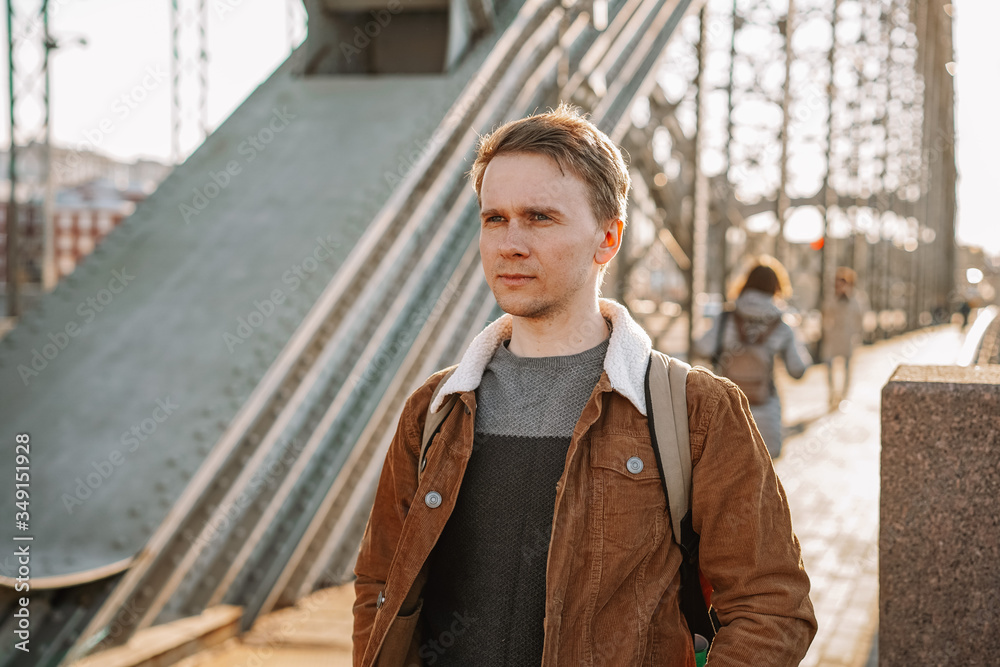 A young ambitious business man walks along the streets, a metal bridge in a Sunny beautiful sunset A young ambitious business man walks along the streets, a metal bridge in a Sunny beautiful sunset