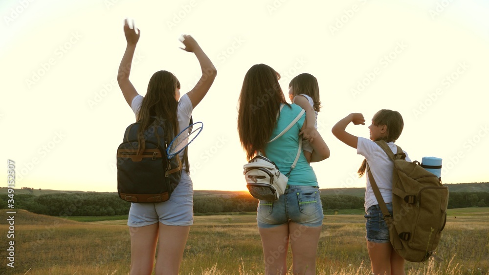 free women travel with backpacks wave their hands and enjoy sunset. adventure and travel concept. Healthy Mom and kids tourists. girls travel. Hiker Girl. mother with daughters travelers