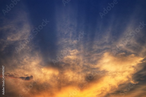 bursting sky. light ray shining through the clouds. cloud caught by last light of the day and grow warm orange yellow in a dramatic fashion. hope God inspiration and silver linings concepts.