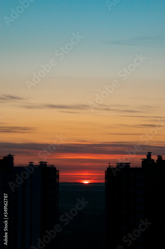 Silhouettes of high-rise buildings against the backdrop of the rising sun. Gradient sky from blue to pink. The morning of a new day. Copy space.