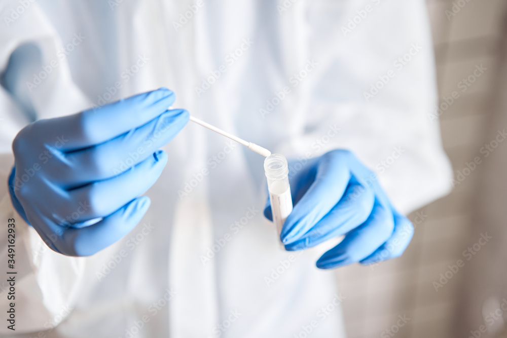Doctor holding swab test tube for 2019-nCoV analyzing. Coronavirus test. Blue medical gloves and protective face mask for protection against covid-19 virus. Coronavirus and pandemic. Doctor holding swab test tube for 2019-nCoV analyzing. Coronavirus test. Blue medical gloves and protective face mask for protection against covid-19 virus. Coronavirus and pandemic.