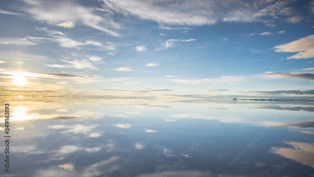 Misty  landscape with clouds and sun reflection in the lake , early morning, calm and quiet, pastel blue and golden color, Salar de Uyuni, Bolivia
