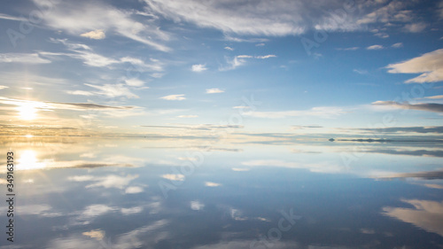 Misty  landscape with clouds and sun reflection in the lake   early morning  calm and quiet  pastel blue and golden color  Salar de Uyuni  Bolivia