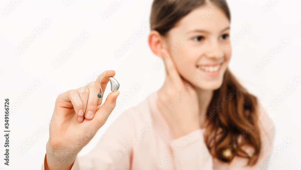 Hearing solution for children. Girl holding a hearing aid, treatment of deafness in children Hearing solution for children. Girl holding a hearing aid, treatment of deafness in children