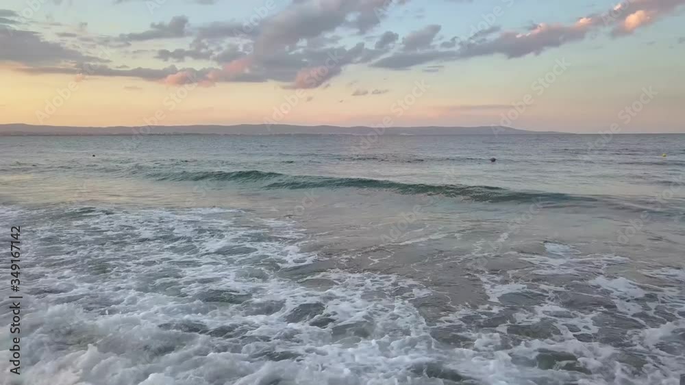 Aerial view of a sea surface with blue water waves under sunset sky. Aerial view of a sea surface with blue water waves under sunset sky.